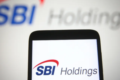 SBIホールディングスのロゴが表示されたスマートフォンと、背景にぼかしたSBI Holdingsのロゴが写った写真